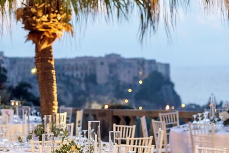 Tavoli eleganti allestiti per un matrimonio al tramonto con vista sul borgo di Tropea